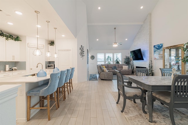 dining area with high vaulted ceiling, recessed lighting, ceiling fan, light wood-type flooring, and a large fireplace