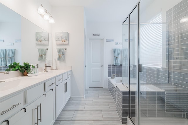 bathroom with double vanity, a stall shower, tiled bath, and a sink