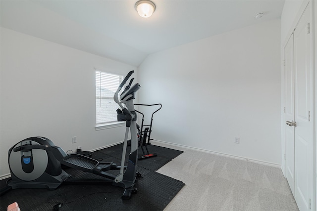 exercise area featuring vaulted ceiling, carpet flooring, and baseboards