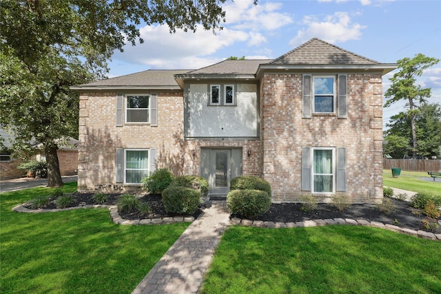 view of front of house with brick siding, a front yard, and fence