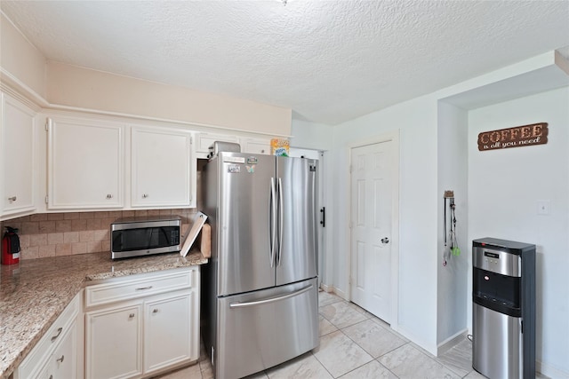 kitchen featuring tasteful backsplash, appliances with stainless steel finishes, white cabinets, and a textured ceiling