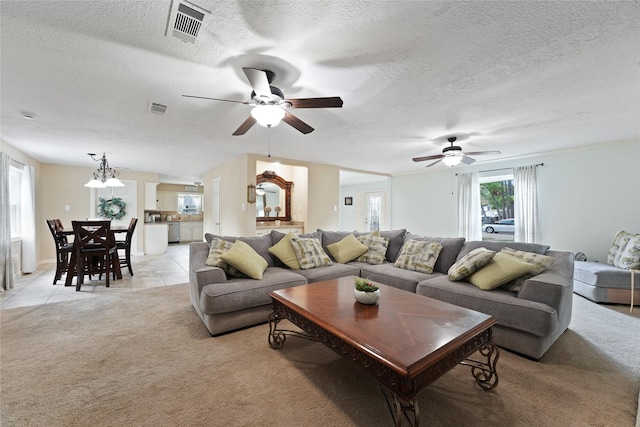 living area featuring a textured ceiling, light tile patterned floors, visible vents, and light carpet