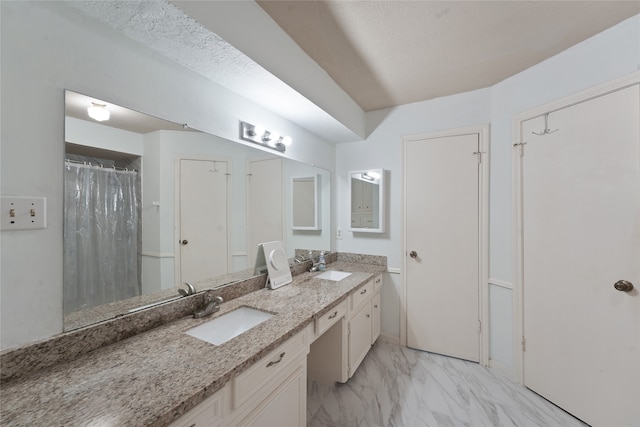 bathroom with a sink, marble finish floor, and double vanity