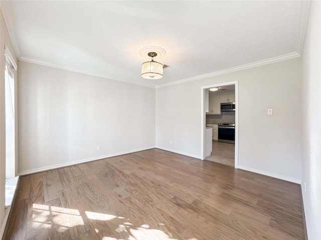 unfurnished room with baseboards, wood finished floors, and ornamental molding