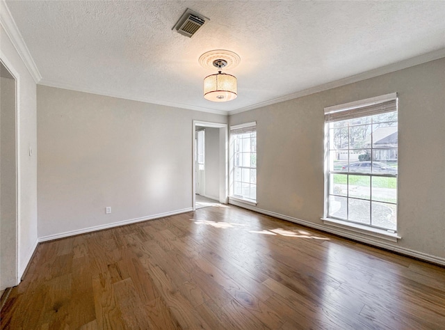 spare room with visible vents, ornamental molding, a textured ceiling, and wood finished floors