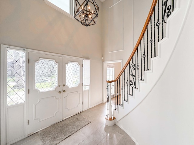 entryway featuring baseboards, a chandelier, stairway, french doors, and a towering ceiling