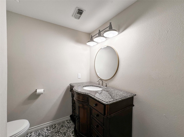 half bath with vanity, baseboards, visible vents, tile patterned flooring, and toilet