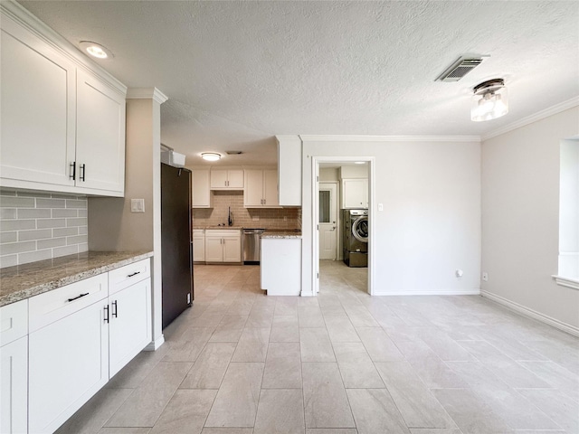 kitchen featuring visible vents, dishwasher, ornamental molding, washer / dryer, and freestanding refrigerator