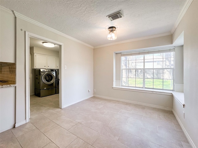 interior space with baseboards, visible vents, light tile patterned flooring, ornamental molding, and washer and clothes dryer