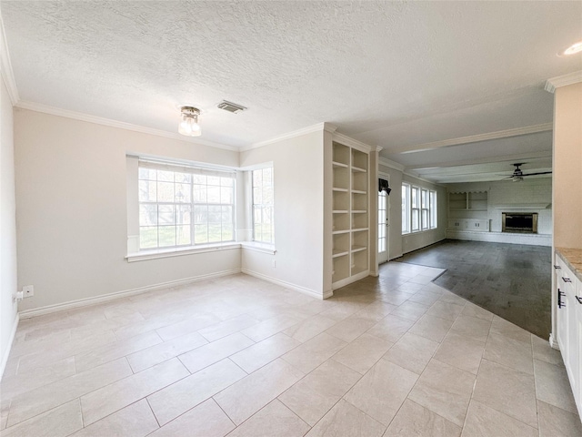 unfurnished living room with visible vents, a fireplace with raised hearth, ornamental molding, a textured ceiling, and a ceiling fan