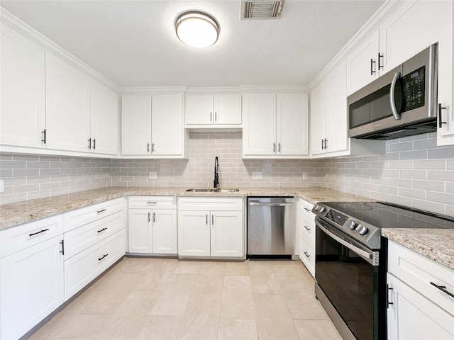 kitchen with visible vents, a sink, backsplash, appliances with stainless steel finishes, and white cabinets