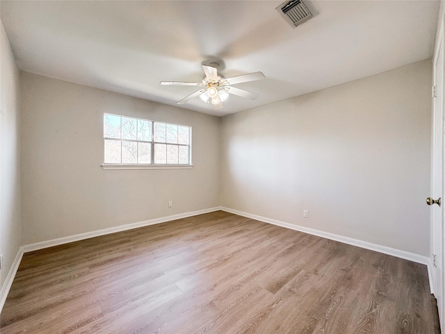 spare room with visible vents, wood finished floors, baseboards, and ceiling fan