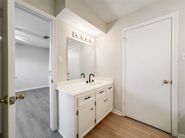 bathroom with vanity, wood finished floors, visible vents, and baseboards