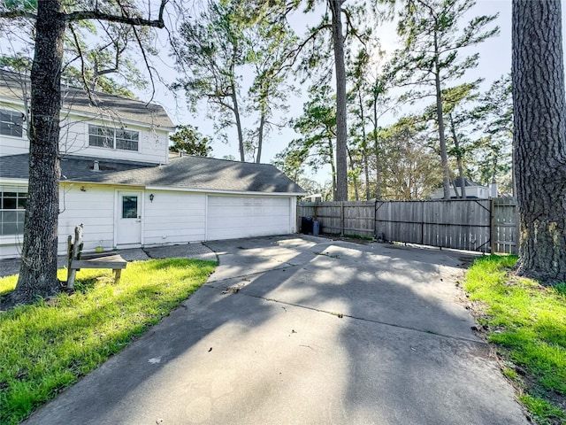 view of home's exterior featuring a garage, driveway, and fence