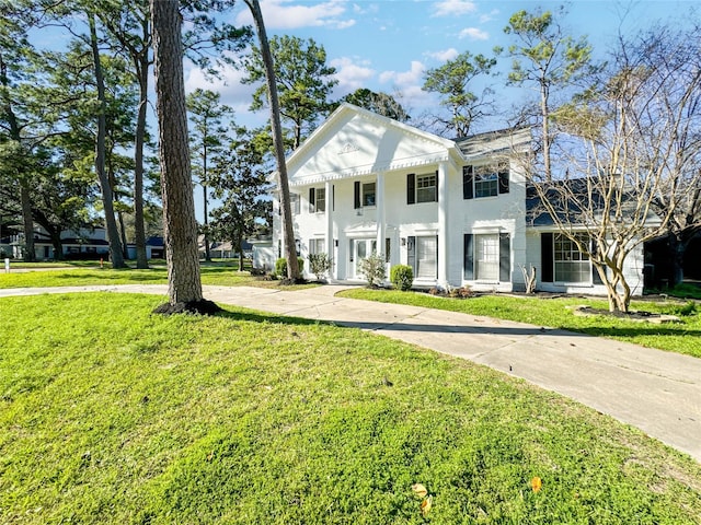 greek revival house with concrete driveway and a front lawn