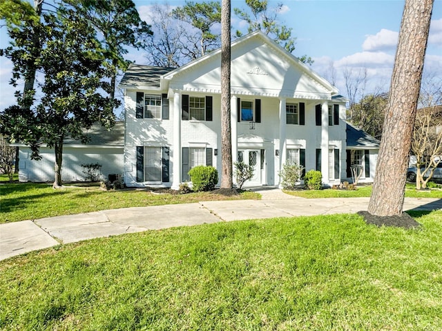 neoclassical home featuring brick siding and a front yard