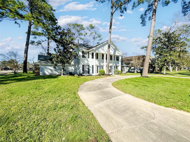 neoclassical home featuring stucco siding, concrete driveway, and a front yard