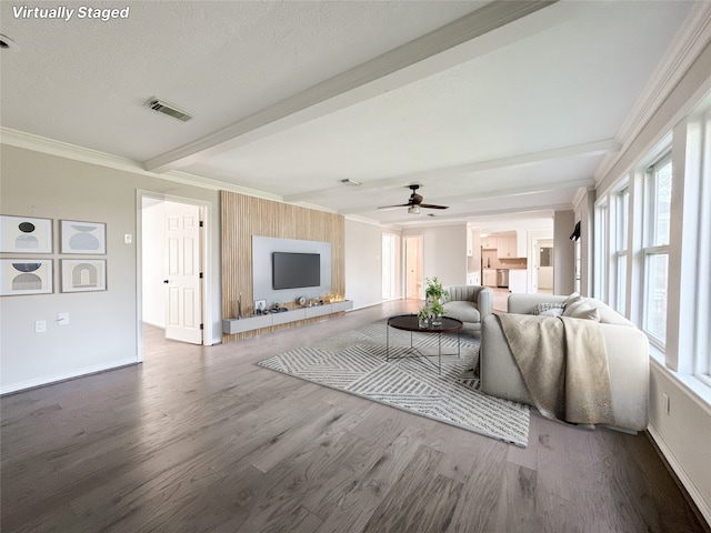 living area featuring visible vents, beam ceiling, wood finished floors, crown molding, and baseboards