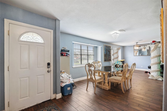 dining space featuring dark wood-style floors, visible vents, a textured ceiling, and baseboards