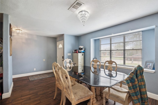 dining area with a textured ceiling, wood finished floors, visible vents, and baseboards