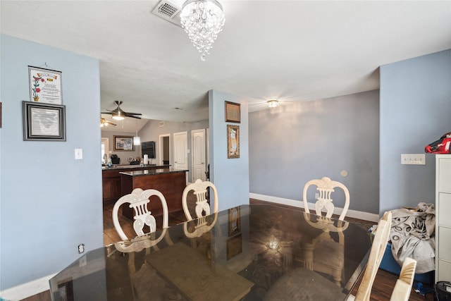 dining space featuring wood finished floors, ceiling fan with notable chandelier, baseboards, and visible vents