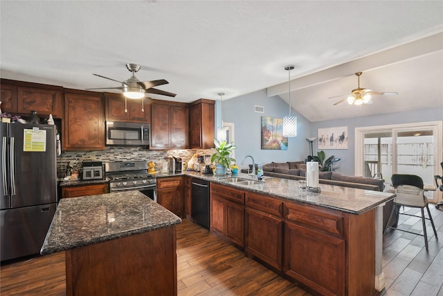 kitchen featuring a peninsula, vaulted ceiling with beams, a sink, stainless steel appliances, and open floor plan