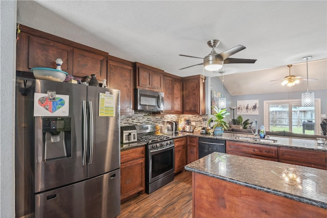 kitchen with tasteful backsplash, dark wood-type flooring, dark stone counters, appliances with stainless steel finishes, and a sink