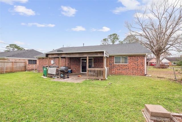 back of house featuring brick siding, a shingled roof, a lawn, a fenced backyard, and a patio