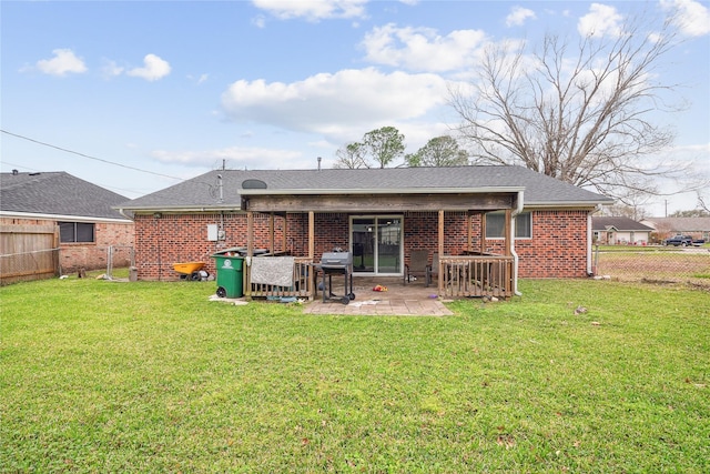 rear view of property featuring brick siding, a fenced backyard, a yard, and a patio