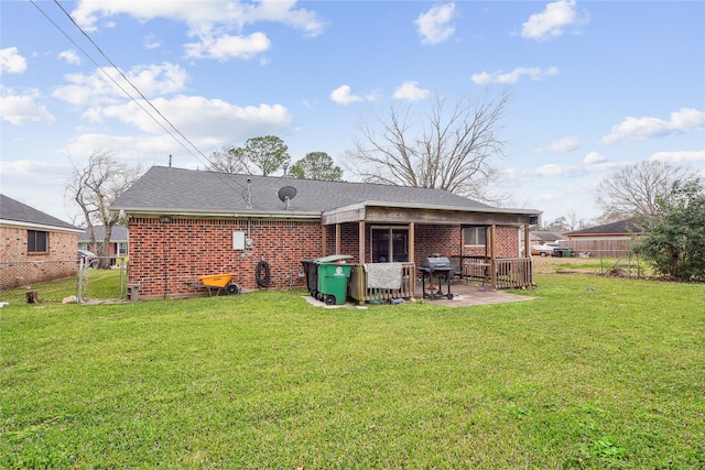 back of property with brick siding, a yard, a patio area, and fence