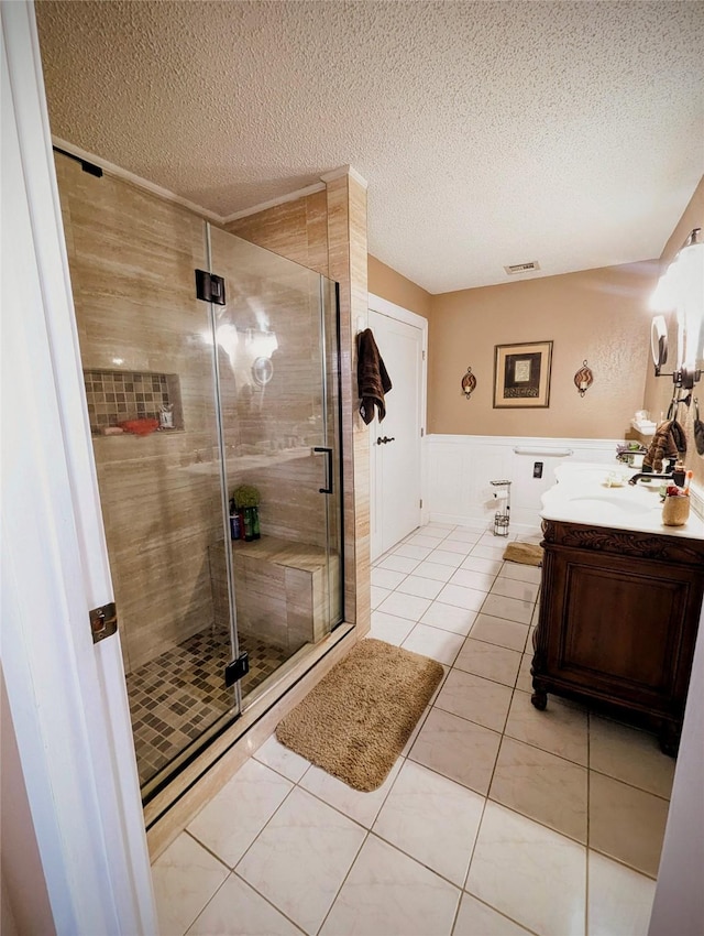 3902 Moore Cemetery Rd, Groveton, TX 75845 - bathroom with vanity, a textured ceiling, a stall shower, wainscoting, and tile patterned floors