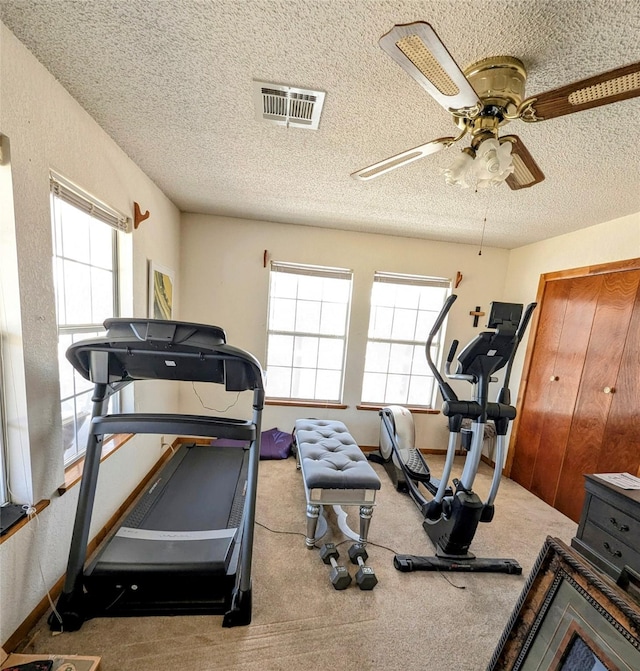 workout area featuring visible vents, a ceiling fan, a textured ceiling, carpet flooring, and baseboards