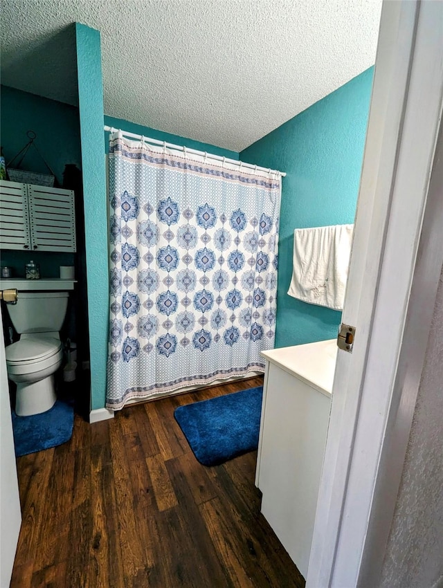 full bath with a shower with curtain, toilet, a textured ceiling, wood finished floors, and a textured wall