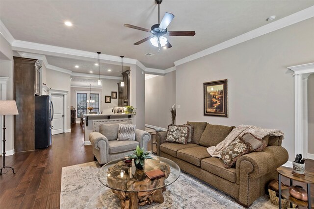 living room featuring ornamental molding, dark wood-style floors, baseboards, and ceiling fan