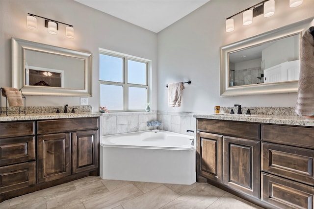 full bathroom with two vanities, a bath, and a sink