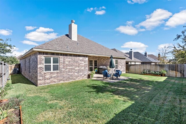 rear view of house featuring brick siding, a fenced backyard, a yard, and a patio