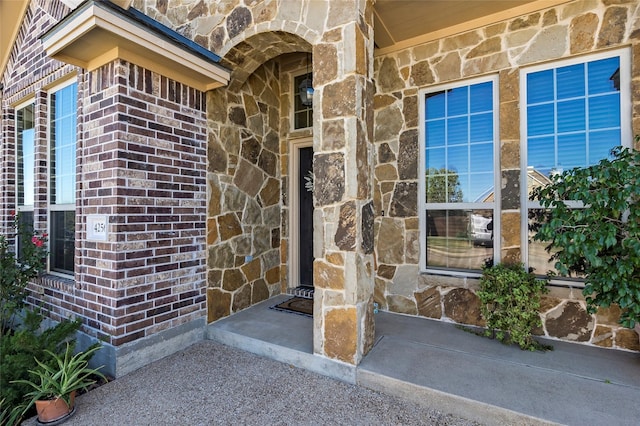 view of exterior entry featuring stone siding and brick siding