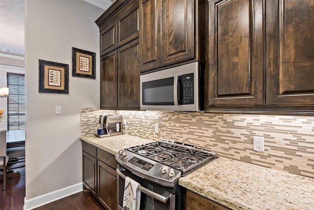 kitchen with dark brown cabinetry, decorative backsplash, appliances with stainless steel finishes, and ornamental molding