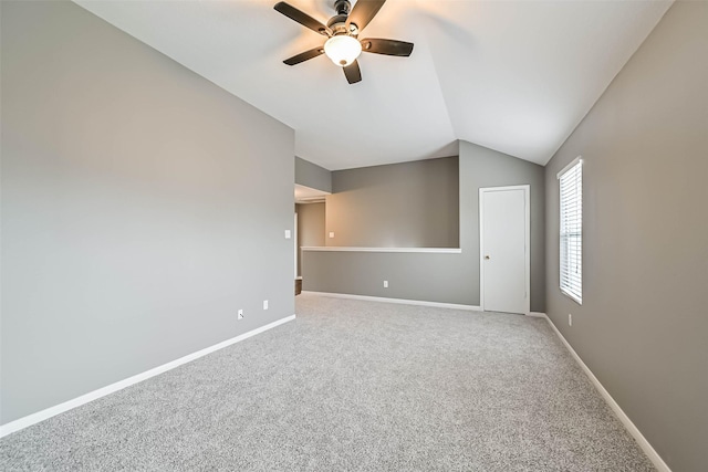 carpeted spare room with ceiling fan, baseboards, and vaulted ceiling