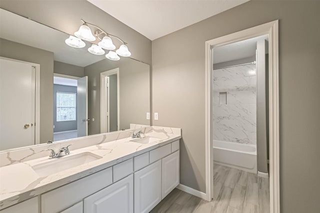 full bath with double vanity, wood finished floors, baseboards, and a sink