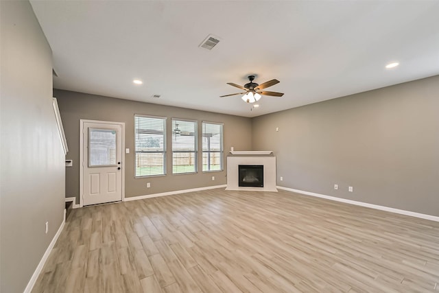 unfurnished living room featuring visible vents, light wood-style flooring, baseboards, and a fireplace with flush hearth