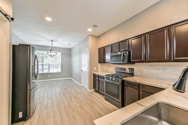 kitchen featuring dark brown cabinets, baseboards, decorative backsplash, light wood-style flooring, and appliances with stainless steel finishes