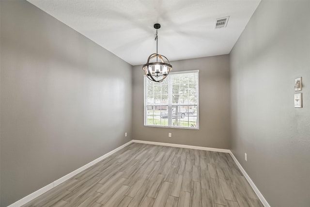 unfurnished room featuring light wood finished floors, visible vents, baseboards, and an inviting chandelier