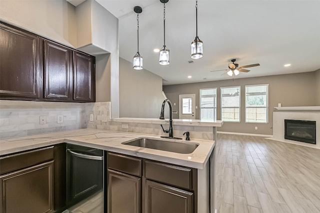 kitchen featuring tasteful backsplash, dark brown cabinets, open floor plan, a peninsula, and a sink