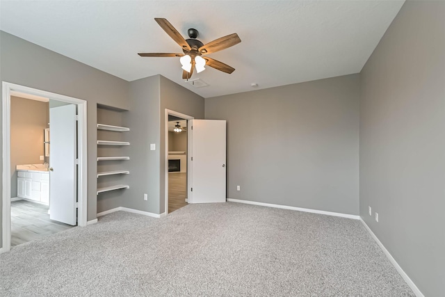 unfurnished bedroom with baseboards, light colored carpet, ensuite bathroom, and a spacious closet