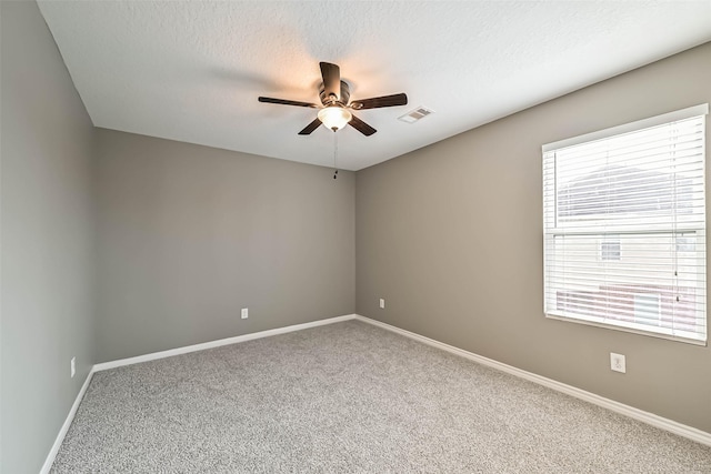 spare room featuring baseboards, visible vents, carpet floors, ceiling fan, and a textured ceiling