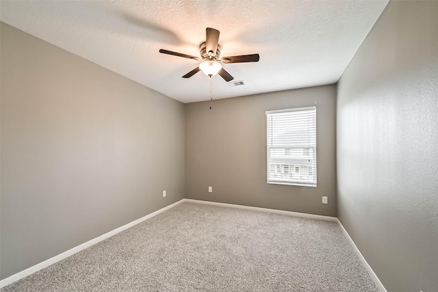 spare room with visible vents, a textured ceiling, carpet floors, baseboards, and ceiling fan