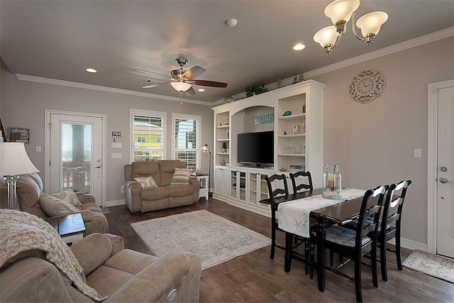 living area with dark wood finished floors, ceiling fan with notable chandelier, baseboards, and ornamental molding