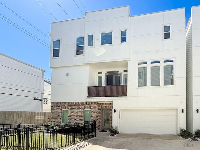 multi unit property with stucco siding, a fenced front yard, a balcony, concrete driveway, and brick siding