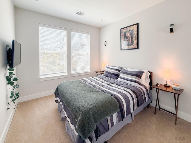 bedroom featuring visible vents, light colored carpet, and baseboards